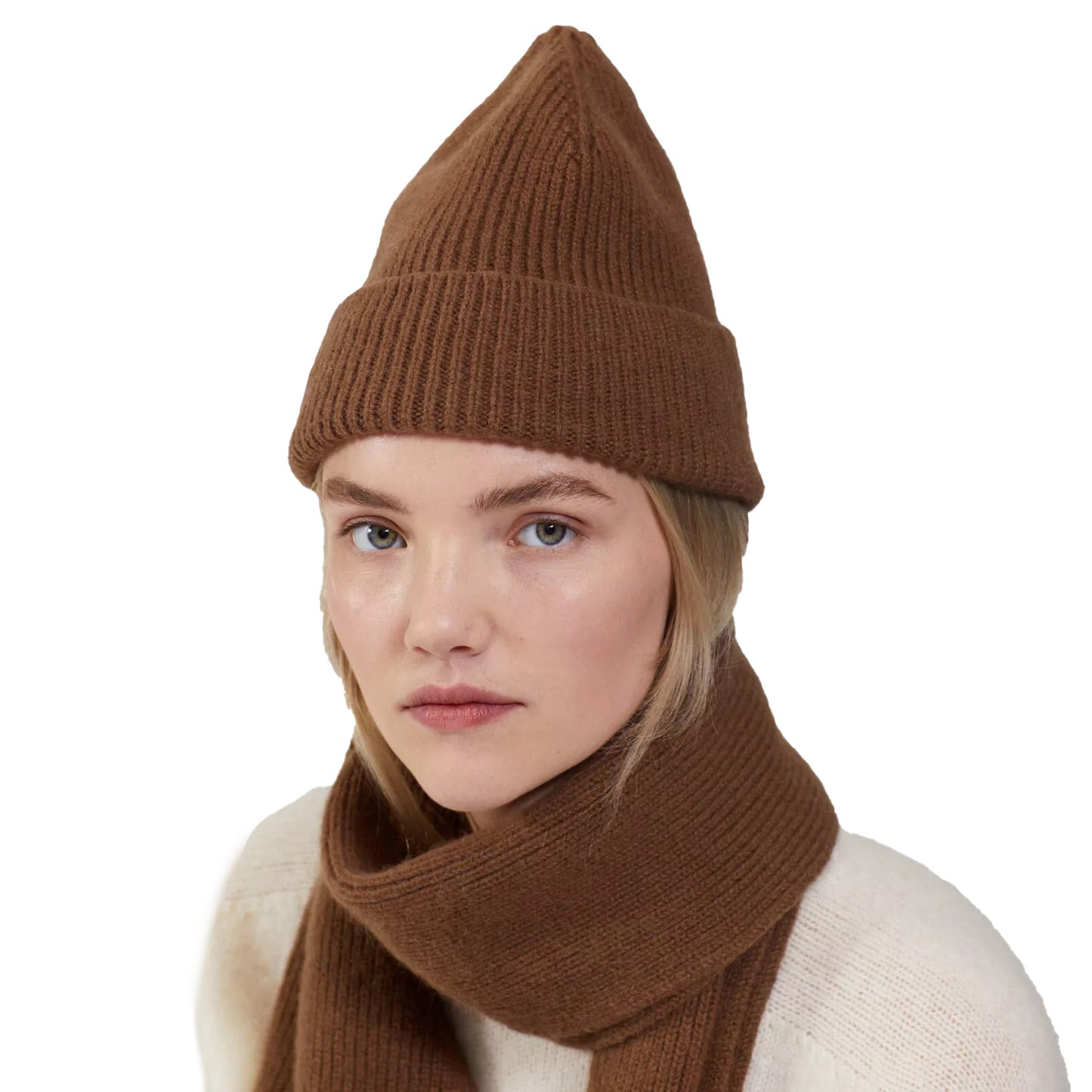 A person is seen wearing a brown lambswool beanie by Le Bonnet and a scarf, paired with a white sweater, against a plain white background.