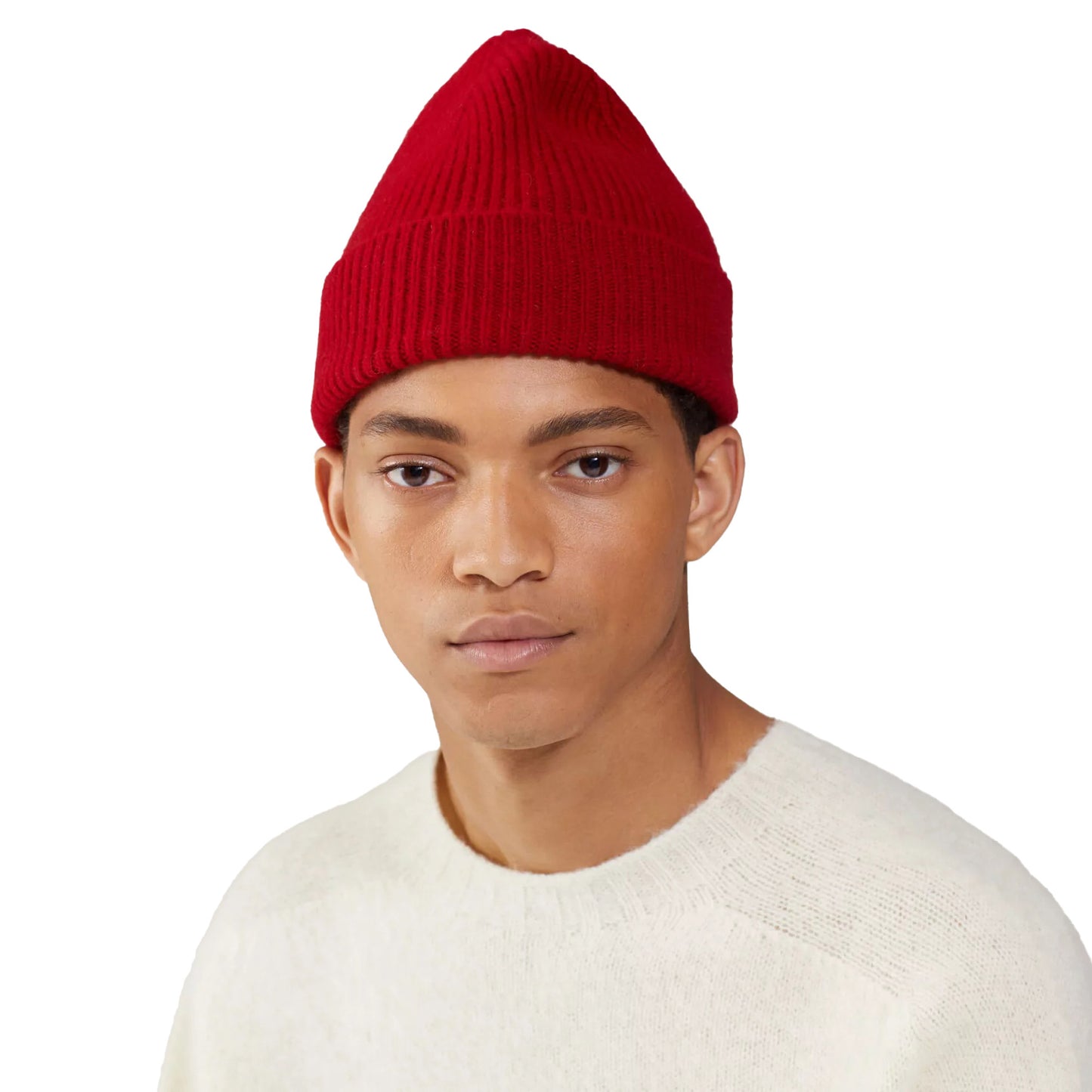 A person wearing a red Le Bonnet ribbed beanie and a white sweater stands against a white background.