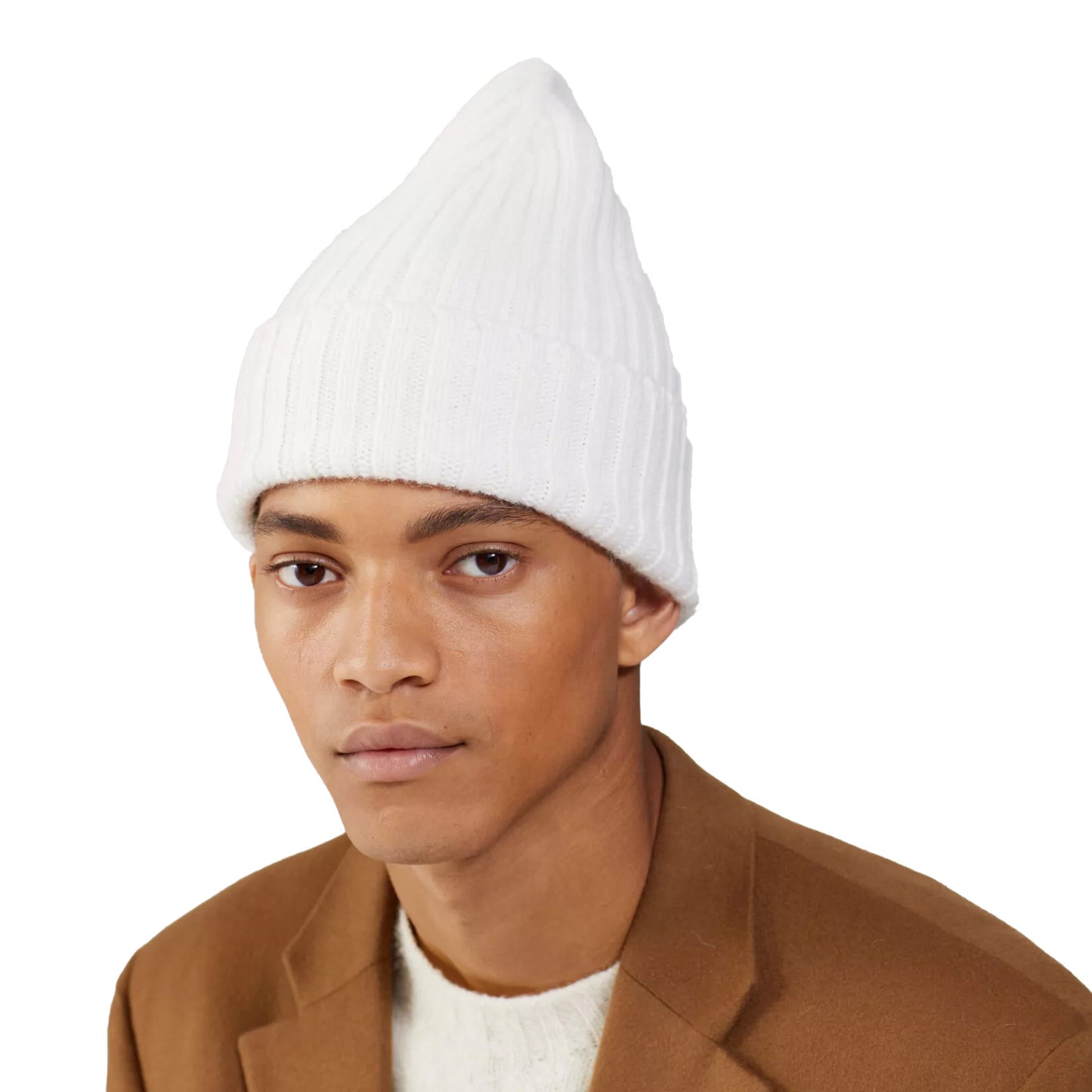 Someone wore a Le Bonnet Large Beanie, known for its chunky knit and extreme comfort, along with a brown jacket against a plain background.