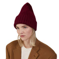 Dressed in a vibrant red "Large Beanie" by Le Bonnet, paired with a brown coat over a white top, the individual exudes extreme comfort while gazing to the side against a pristine white background.