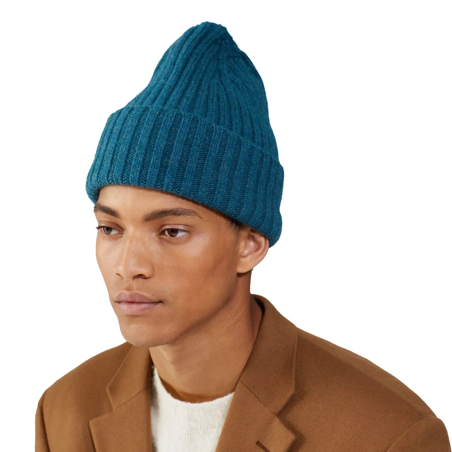 A person wearing a chunkier Le Bonnet Large Beanie in teal and a brown coat over an extremely comfortable white sweater, facing slightly to the right.