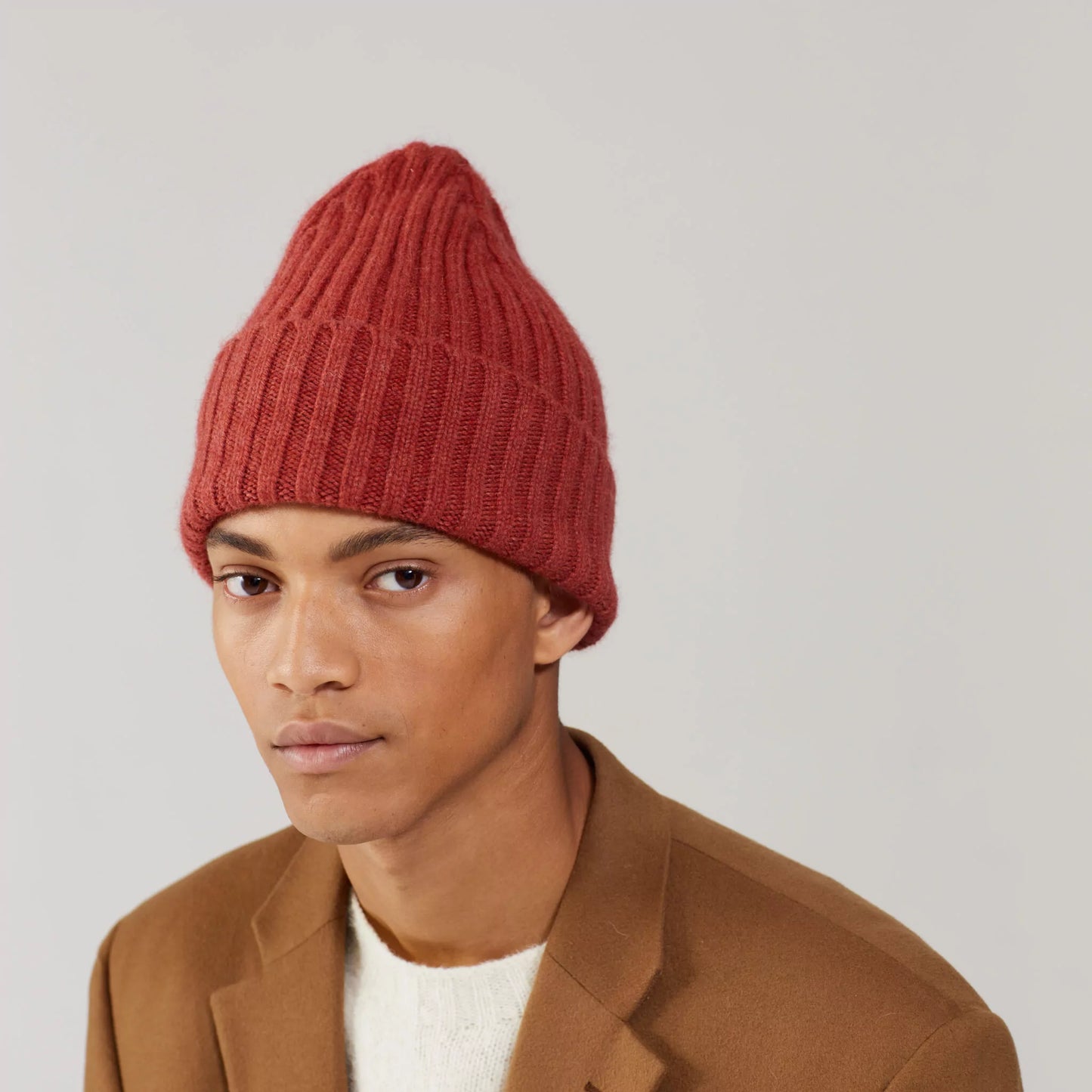 Person wearing a Terra Le Bonnet beanie, a cream sweater, and a brown jacket against a plain background.