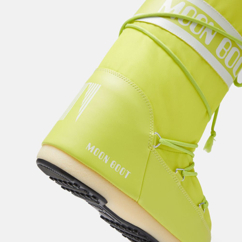 Close-up of the Icon Nylon by Moon Boot in lime green, featuring black soles, padded design, decorative laces, and a water-repellent finish for durability.