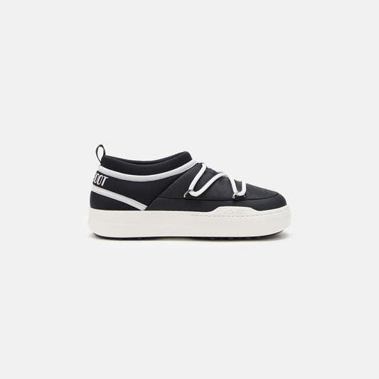 The "Park Icon" by Moon Boot is a black slip-on sneaker with an ultra-flexible design, a white sole and laces, plus white text on the heel, shown on a plain white backdrop.