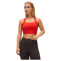 A woman stands wearing the moisture-wicking Kay Sports Bra from Rohnisch, made from recycled polyester, paired with black workout leggings against a white background.