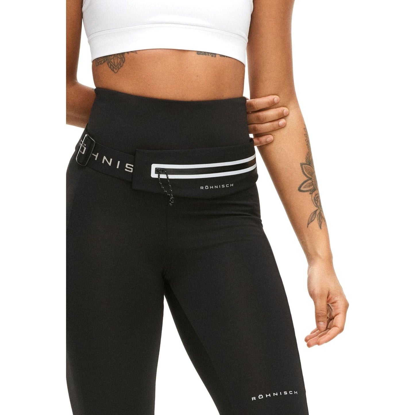 A person wearing black high-waisted athletic leggings made from recycled material, paired with the Issa Expandable Running Belt in black by On Running and a white crop top.