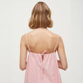 Back view of a person with shoulder-length hair, wearing the Strap Dress Petite by Aiayu, featuring a pink and white striped sleeveless design.