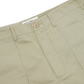 Close-up of Universal Works' Fatigue Pant Twill in Stone, showcasing the button, zipper, and a partially visible label inside the waistband.