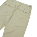 Universal Works' Fatigue Pant Twill in Stone features two buttoned back pockets and is shown lying flat.