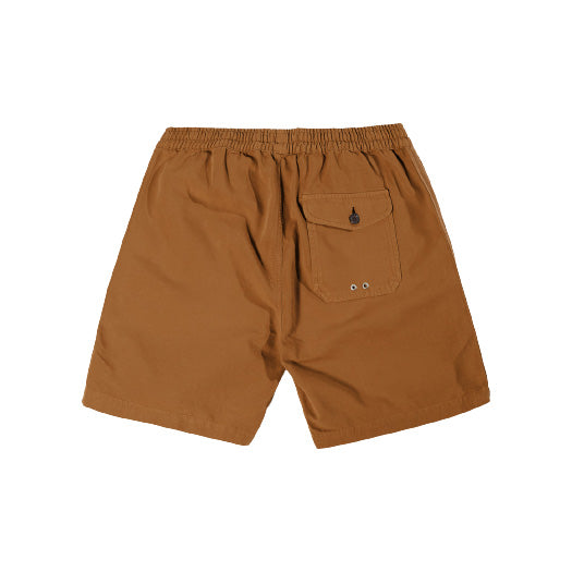 The Beach Short in Cumin by Universal Works features an above-the-knee design, elastic waist, and a button-closure single back pocket, ideal for beach outings.