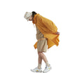 A person wearing a beige outfit, Universal Works' BEACH PARKA in orange, white sneakers, and a bucket hat walks with their head down.