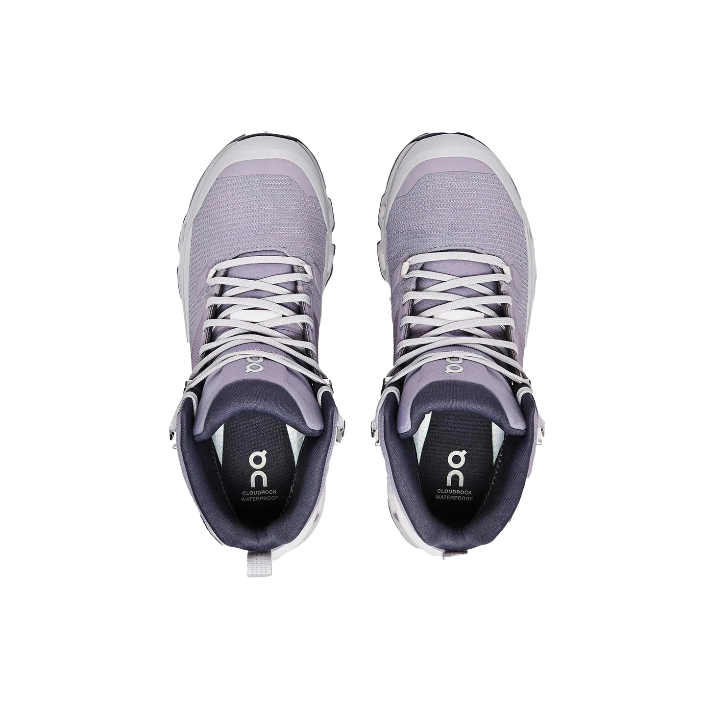 A pair of Women's Cloudrock 2 Waterproof shoes in purple from On Running, featuring a CloudTec® outsole and white laces, is viewed from above on a black background, highlighting their innovative design.