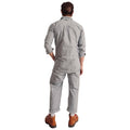 A person stands facing away, wearing a Westerlind Climbing Jumpsuit, Light Grey-1 made of durable cotton ripstop with rolled-up pant legs and brown work boots.